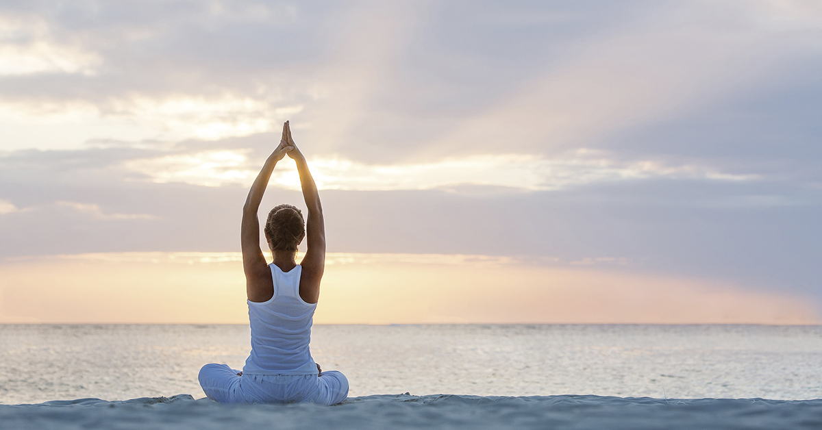 mujer practicando yoga en la playa