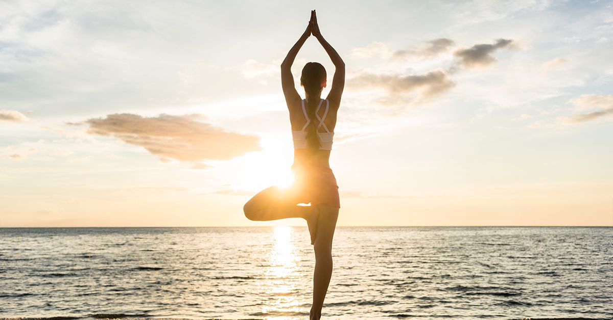 Woman striking a yoga pose on the beach